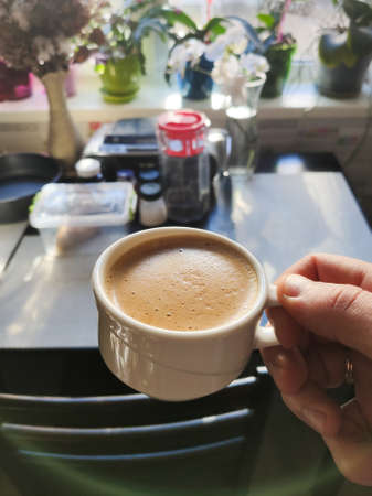 a cup of espresso coffee in hand in the kitchenの写真素材