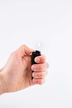 a gas lighter in hand burns fire on a white backgroundの写真素材