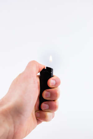 a gas lighter in hand burns fire on a white backgroundの写真素材