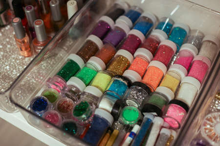 a jars of glitter in different colors in a manicure salon for nailsの写真素材