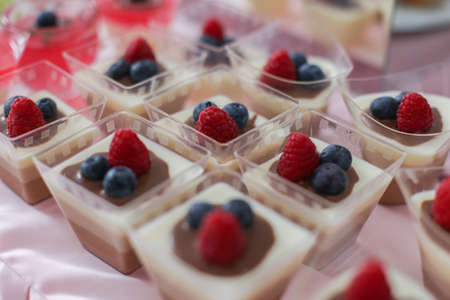 a portions of sweet cakes with raspberries and blueberries for dessertの写真素材
