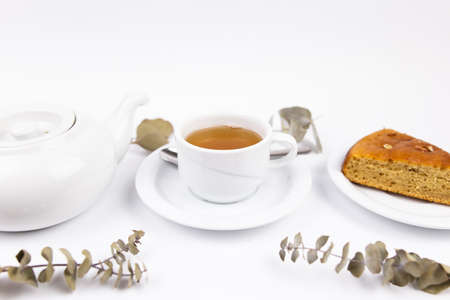 a white tea set with teapot tea and saucers and pie for breakfastの写真素材