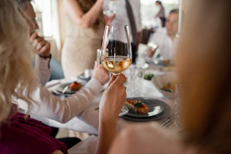 glass of white wine in a girl's hand in a restaurantの写真素材