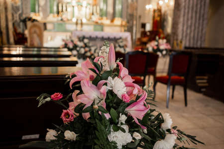 a decor of flowers in the Catholic Church and wooden benchesの写真素材