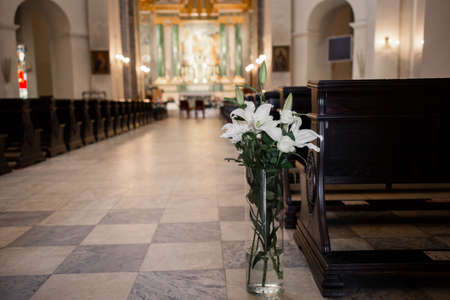 a decor of flowers and a wooden bench in the Catholic Churchの写真素材