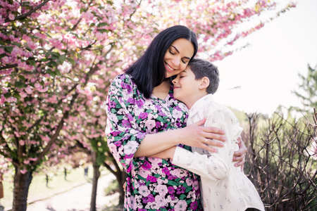 pregnant woman with eldest son in sakura flowers in springの写真素材