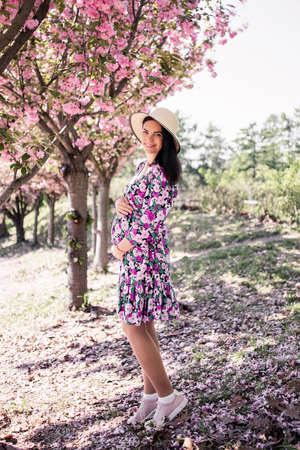 pregnant girl in a dress near the sakura in the gardenの写真素材