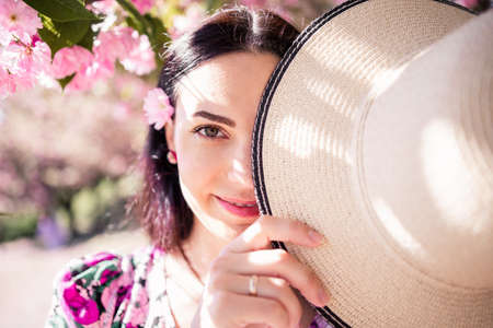 a brunette girl in a straw hat in a blooming gardenの写真素材