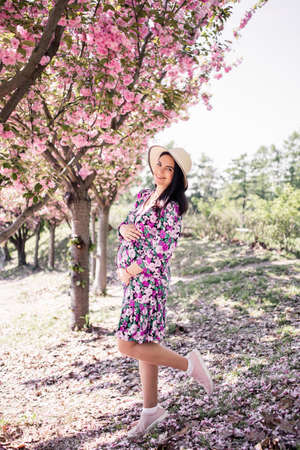 pregnant girl in a dress near the sakura in the gardenの写真素材