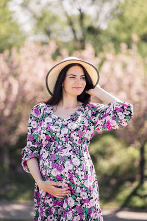 pregnant girl in a dress near the sakura in the gardenの写真素材