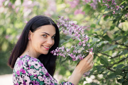 a woman with dark hair in a straw hat near cherry blossoms in springの写真素材