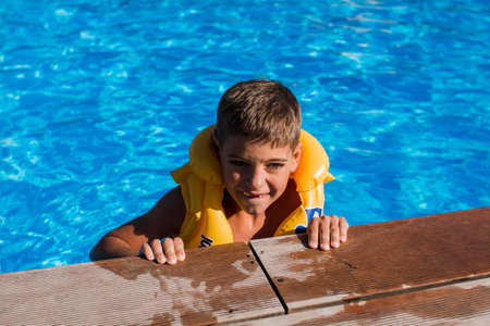 a boy in an inflatable jacket in the pool in summer