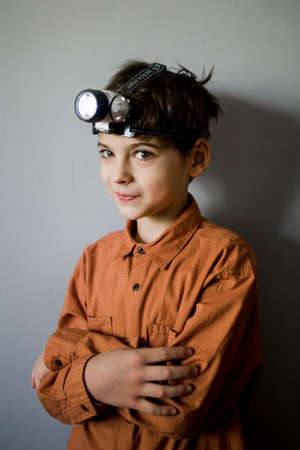a boy on the background of the wall with a flashlight on his headの写真素材