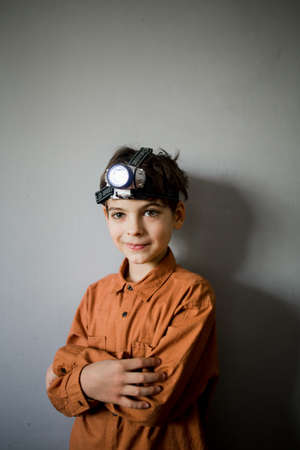 a boy on the background of the wall with a flashlight on his headの写真素材
