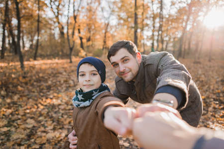 a boy with dad in autumn forest with orange leavesの写真素材