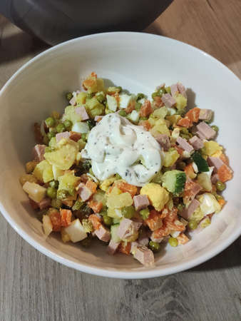 a olivier salad in a white bowl in the kitchenの写真素材
