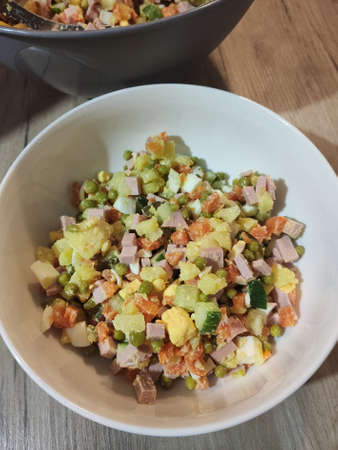 a olivier salad in a white bowl in the kitchenの写真素材