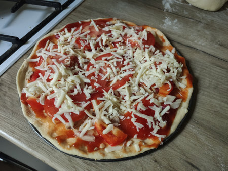 a homemade pizza with tomatoes on the kitchen tableの写真素材