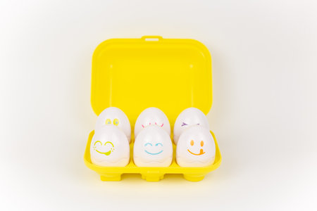 a toy plastic eggs in a yellow case on a white backgroundの写真素材