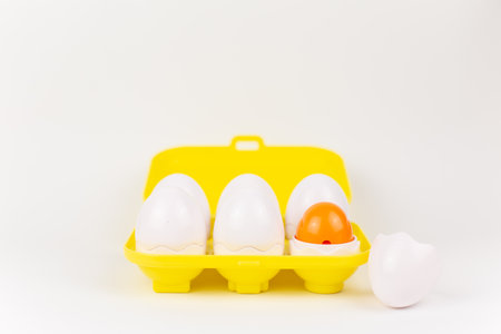 a toy plastic eggs in a yellow case on a white backgroundの写真素材