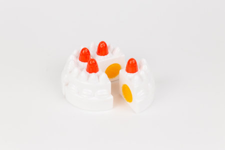 a plastic toy children's cake with white cream on a white backgroundの写真素材