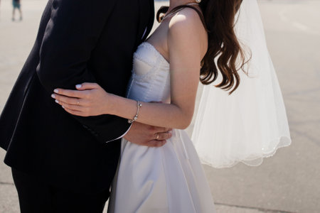 groom and the bride in a wedding dress stand together on the streetの写真素材