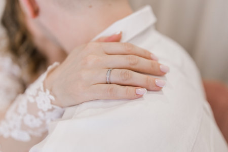 bride puts her hand with the wedding ring on the groom's shoulderの写真素材