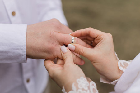 groom puts a gold wedding ring on the bride's fingerの写真素材