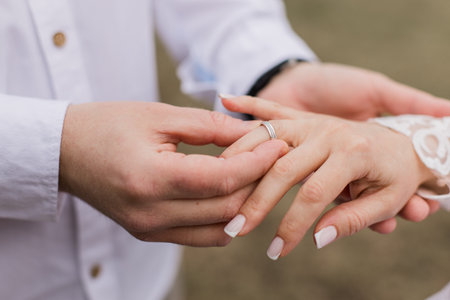 groom puts a gold wedding ring on the bride's fingerの写真素材
