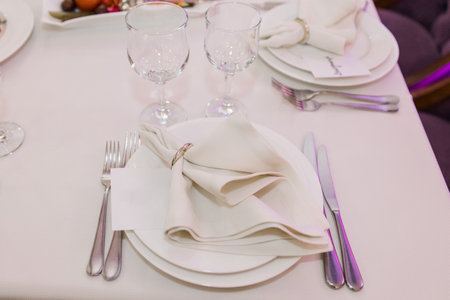 a plate, knife and fork set on a festive table in a restaurant at a wedding birthday celebrationの写真素材