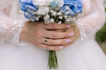 bride in a white dress holds a wedding bouquet at the weddingの写真素材