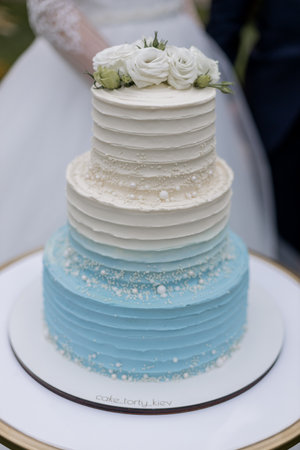 a beautiful wedding cake near the arch with flowers in the evening