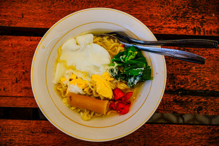 Noodles with egg and vegetables on wooden table, Kuningan, Indonesia.