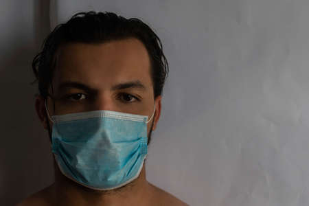 white young man with wavy black hair, with a mask, facing the camera, with white backgroundの写真素材