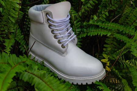 White boot shoe with low platform sole in the foreground, surrounded by green grassの写真素材