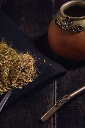 Yerba mate and calabash with bambilla on a black wooden background-traditional argentinian and...