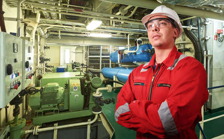 Ship's mechanic near marine diesel generators on a merchant ship in the engine room with all the...