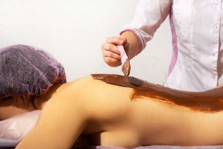 Chocolate massage for healthcare design. Beauty treatment. Beauty salon. Spa skincare treatment. Chocolate skincare mask. Female body. Woman beauty, body care. Wellness massage.の写真素材
