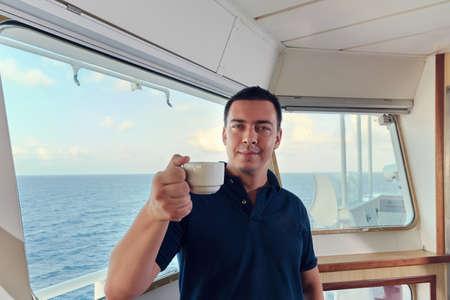 Navigation offcier Pilot on the bridge of a ship underway with cup of coffee. Line of horizon and...