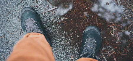 Man staingg during rainy autumn weather in a puddle in a waterproof tracking shoes. Fall weather Concept. All season adventure concept. Muddy background fo any fall article.の写真素材
