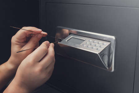 Close-up of Thief's hands attempting to Break Home Money Safe and perform Robbery. Safety and Home Security concepts.の写真素材