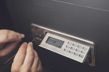Close-up of Thief's hands attempting to Break Home Money Safe and perform Robbery. Safety and Home Security concepts.の写真素材