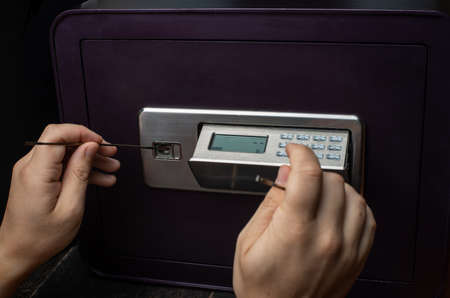Close-up of Thief's hands attempting to Break Home Money Safe and perform Robbery. Safety and Home Security concepts.の写真素材