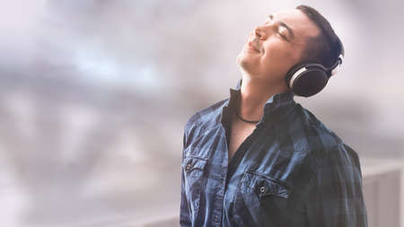 Man with headphones on pastel background. Black headphones. Leisure concept. Technology background. Digital gadget. Smart person. Entertainment concept.の写真素材