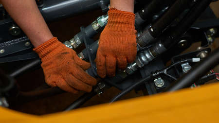 Low key photo of hydraulic pipes maintenance on heavy industry machine in a garage.の写真素材