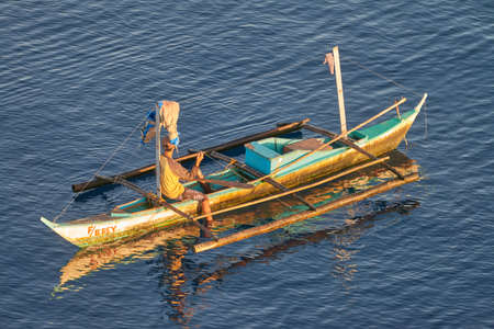 Cebu, Philippines - Circa April 2019: Traditional peaceful philippines fisherman on a wooden boat catching fish on a sunrise close to Cebu Island, Philippines. Beautiful calm sunrise. Aerial view, aerial photography.のeditorial素材