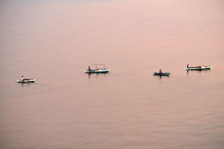 Cebu, Philippines - Circa April 2019: Traditional peaceful philippines fisherman on a wooden boat catching fish on a sunrise close to Cebu Island, Philippines. Beautiful calm sunrise. Aerial view, aerial photography.のeditorial素材