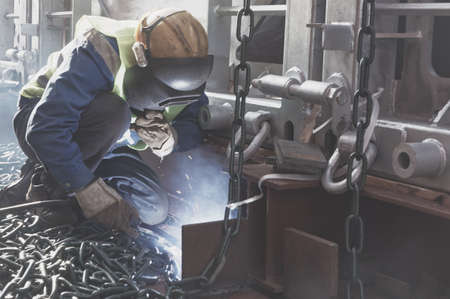Welder doing welding on deck of ship lashing cargo for sea shipping on background of lenty lashing...
