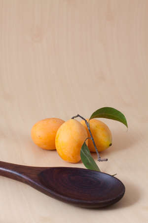 Three ripe marian plums with a wooden ladleの写真素材