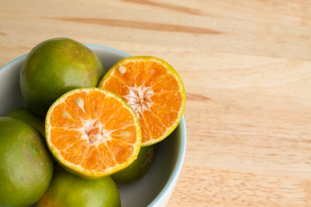 Orange fruits in a bowl on wooden tableの写真素材